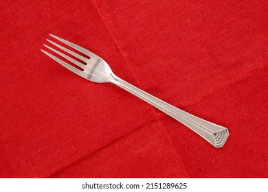 One Metal Fork On A Red Linen Napkin, Macro, Top View.