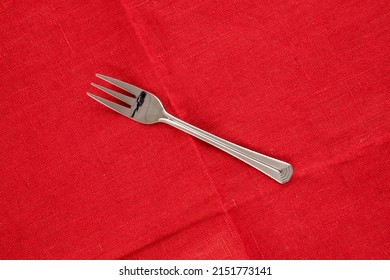 One Metal Fork On A Red Linen Napkin, Macro, Top View.