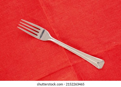 One Metal Fork On A Red Linen Napkin, Macro, Top View.