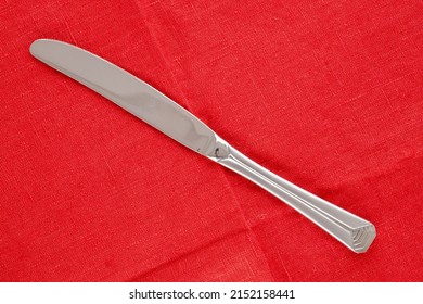 One Metal Knife On A Red Linen Napkin, Macro, Top View.