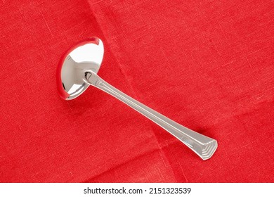 One Metal Ladle On A Red Linen Napkin, Macro, Top View.