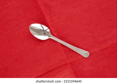 One Metal Spoon On A Red Linen Napkin, Macro, Top View.