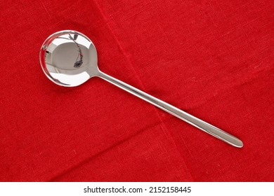 One Metal Spoon On A Red Linen Napkin, Macro, Top View.