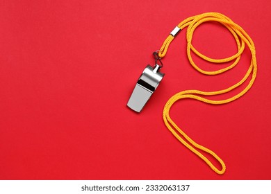 One metal whistle with cord on red background, top view. Space for text