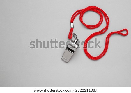 One metal whistle with red cord on light grey background, top view. Space for text