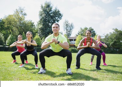 Noch einmal Mädchen! Gruppe sportlicher junger Frauen in Sportbekleidung, die körperliche Übungen mit dem Reisebus im grünen Sommerpark im Freien mit dem Reisebus durchführen
