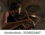 One music player with classic wooden violin. Soloist musician playing sounds of calm acoustic melody by bow closeup. Work of pretty woman as orchestral violinist indoors at large room of great theater