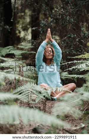 One natural healthy woman meditate end practice yoga exercise in the forest green woods enjoying outdoor leisure activity in the nature. Wellbeing and mindful exercise people outside. People meditate