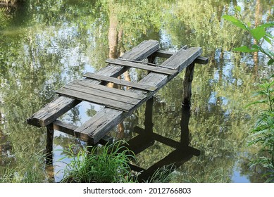 One Old Broken Gray Wooden Footbridge Over Lake Water Near The Shore