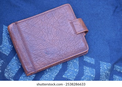 one old closed brown leather wallet lies on a black gray table - Powered by Shutterstock