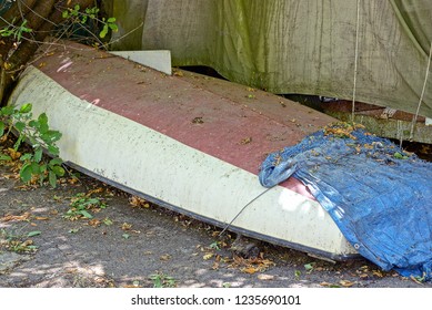 one old dirty inverted boat lies on the sidewalk in the street near the wall - Powered by Shutterstock