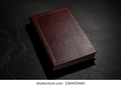 One old hardcover book on black textured table