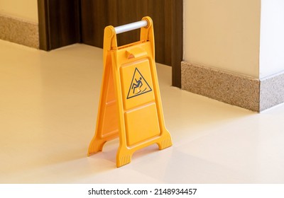 One Orange Caution Slippery Wet Floor Fold Out Sign In The Hallway, Workplace Safety, Accidents Symbol, Risk Of Falling, Warning Abstract Concept, Nobody, Single Object Closeup, No People, Maintenance