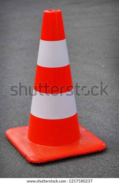 One\
orange and white traffic cone on the asphalt\
road