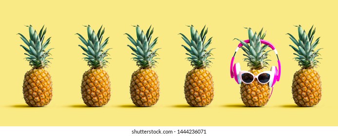 One out unique pineapple wearing headphones on a solid color background - Shutterstock ID 1444236071