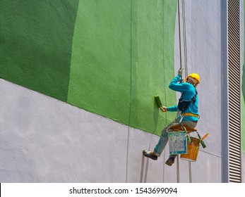 One Painter Is Painting The Exterior Of The Building On A Dangerous Looking Scaffolding Hanging From A Tall Building.