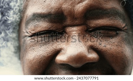 One peaceful wrinkled South American black woman closing eyes in meditation in macro closeup, opening eye staring at camera, detail face of elderly person in 80s