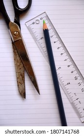 One Pencil, Pair Of Scissors And A Clear Ruler On Lined White Paper.