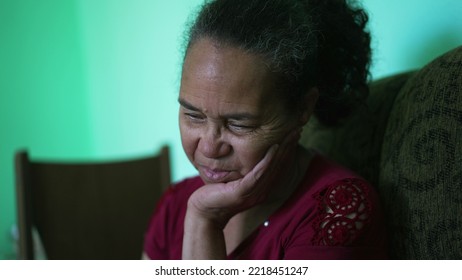 One Pensive Hispanic Older Woman Sitting At Couch. A Contemplative Worried Latin American Senior Person