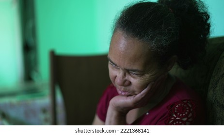 One Pensive Hispanic Older Woman Sitting At Couch. A Contemplative Worried Latin American Senior Person