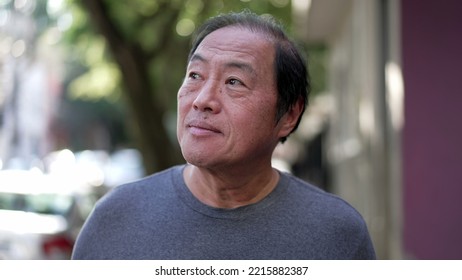 One Pensive Senior Man Having An Idea Breakthrough While Walking Outdoors. Portrait Of A Contemplative Older Middle Aged Asian Person In Contemplation