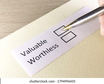 One Person Is Answering Question On A Piece Of Paper. The Person Is Thinking To Choose Valuable Or Worthless.