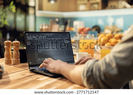 One person coding on laptop in a kitchen representing remote work in IT and software development. Programmer writes source code and uses command-line tools, highlighting engineering at home.