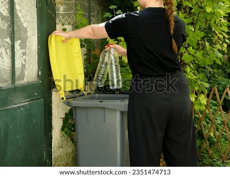 One person making a selective sorting of waste. A woman putting plastic bottles in a yellow bin for recycling.