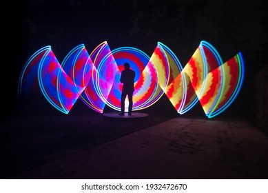 one person standing against beautiful blue red and yellow circle light painting as the backdrop - Powered by Shutterstock