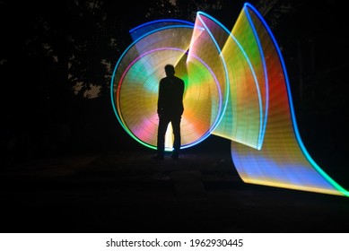 One Person Standing Against Beautiful Rainbow Circle Light Painting As The Backdrop