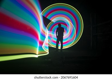 One Person Standing Against Beautiful Rainbow Circle Light Painting As The Backdrop