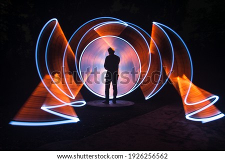 one person standing against beautiful white and red circle light painting as the backdrop