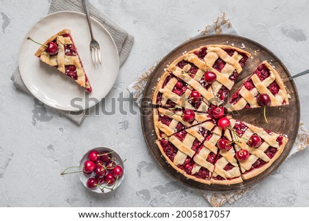 One piece on a plate and the whole homemade cherry pie on white background, top view