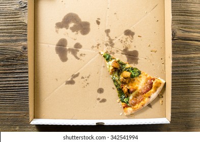 One piece of pizza in cardboard pizza box. Top view