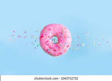 One Pink Flying Sweet Doughnut With Sprincles On Blue