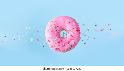 One Pink Flying Sweet Doughnut With Sprincles On Blue