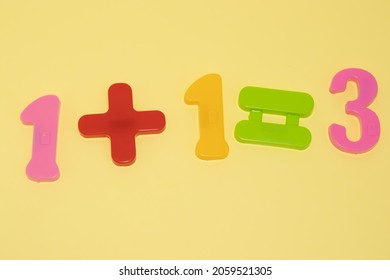 One Plus One Equals Three. Promotion: Three For The Price Of Two.
Wrong Sum One Plus One Equals Three Written.
Colorful Magnetic Toy Pieces On Yellow Background.