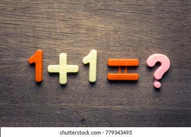One plus one mathematics question by plastic fiqures on wood background