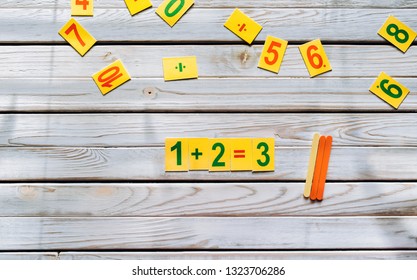 One plus two concept. Mathematics. School knowledge. Primary School. Digits on a wooden background. Doubts and thinking.