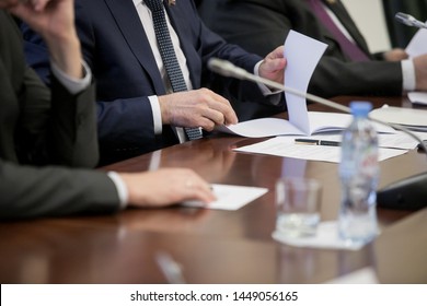 One of politician sitting by table with his hands over document during political summit or conference - Shutterstock ID 1449056165