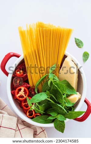One pot pasta. Raw ingredients for pasta: spaghetti, parmesan, vegetables and basil in a saucepan, top view.