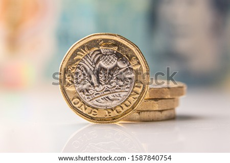 one pound coin with a 10 pound bill in the background