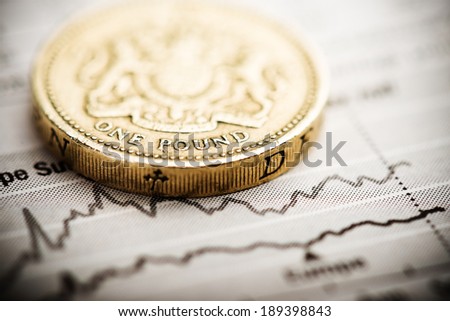 One pound coin on fluctuating graph. Rate of the pound sterling (shallow DOF) 