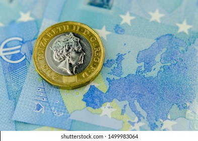 One pound coin on top of 20 Euros banknote, next to the map of the EU. Close up photo, flat lay view. Concept for currency exchange, finance and BREXIT. 