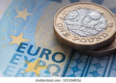 One pound coin placed on top of 20 EURO banknote with visible words "EURO" translated in different languages. Concept. Selective focus. Macro.