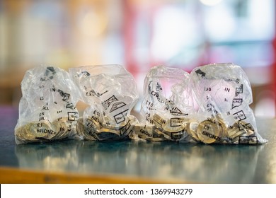 One Pound Coins In Banking Money Bags Sitting On A Wooden Counter Top