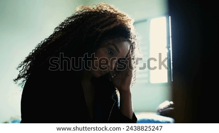 One preoccupied middle-aged black woman feeling anxiety and worry by bedside contemplation. Thoughtful 50s person in quiet despair indoors