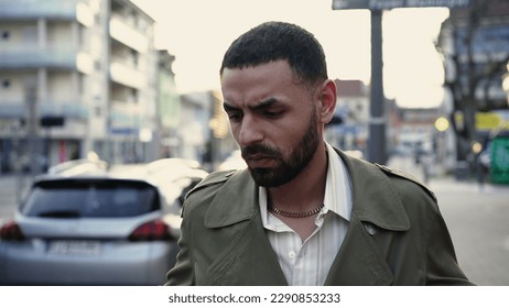 One preoccupied pensive young Arab man walks in city street sidewalk with thoughtful anxious expression about future. Worried emotion of a Middle Eastern male person - Shutterstock ID 2290853233