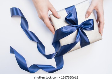 One Present Box With Blue Bow In A Woman's Hands On Isolated Background.