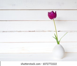 One Purple Spring Tulip In A Small Modern Light Gray Vase On A White Table And Against Distressed Shiplap Wood Board Background With Extra Room Or Space For Copy, Text Or Your Design.